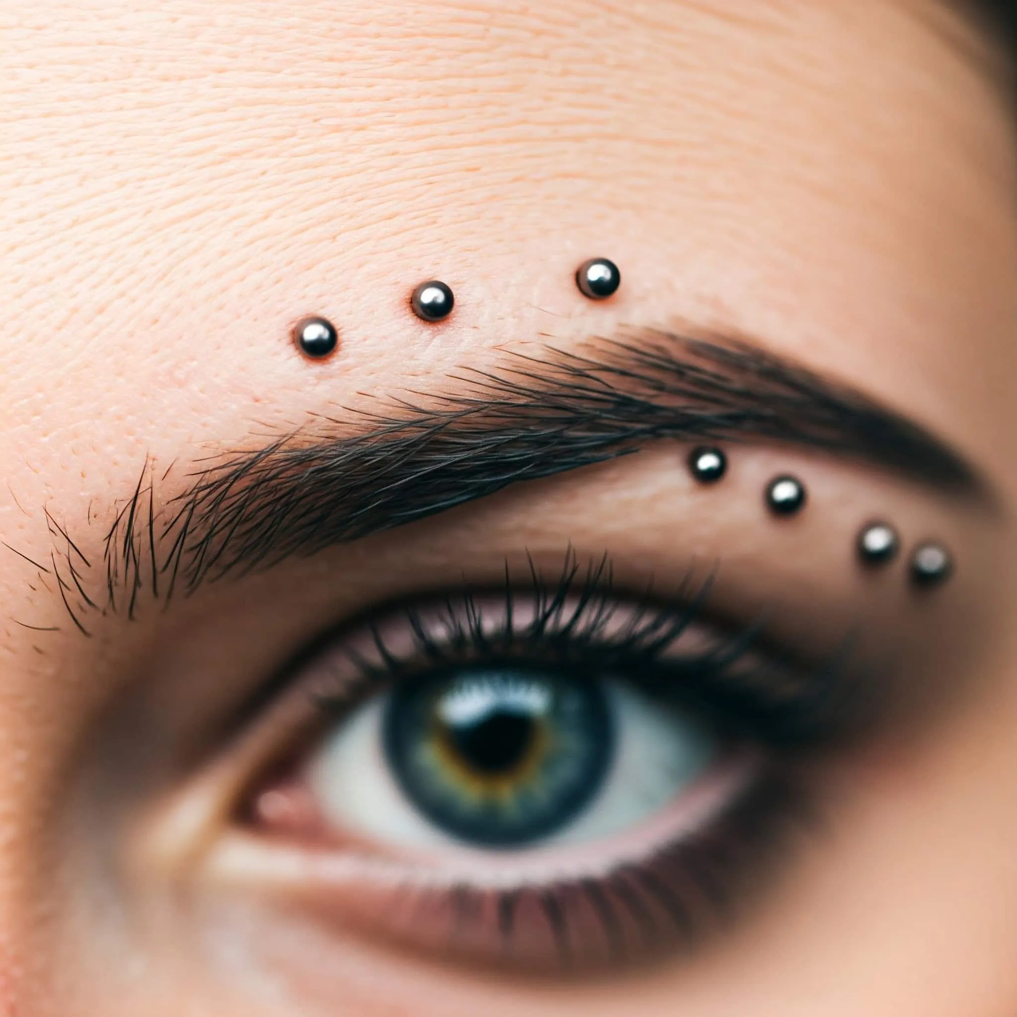 A woman with multiple eyebrow piercings, reflecting her individuality and contemporary aesthetic in body art.