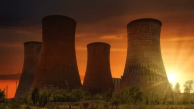 A row of tall industrial cooling towers silhouetted against a fiery sunset, showcasing a key component of Russia's energy sector.