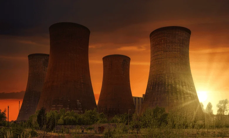 A row of tall industrial cooling towers silhouetted against a fiery sunset, showcasing a key component of Russia's energy sector.