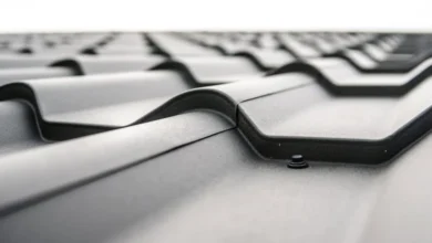 Close-up of a modern metal roof with interlocking panels, showing texture and a screw fastening point for optimal roof maintenance.