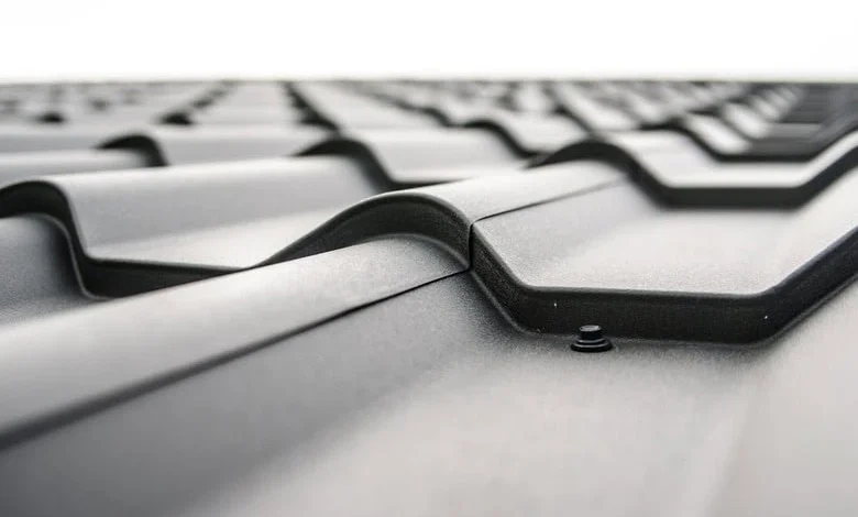 Close-up of a modern metal roof with interlocking panels, showing texture and a screw fastening point for optimal roof maintenance.